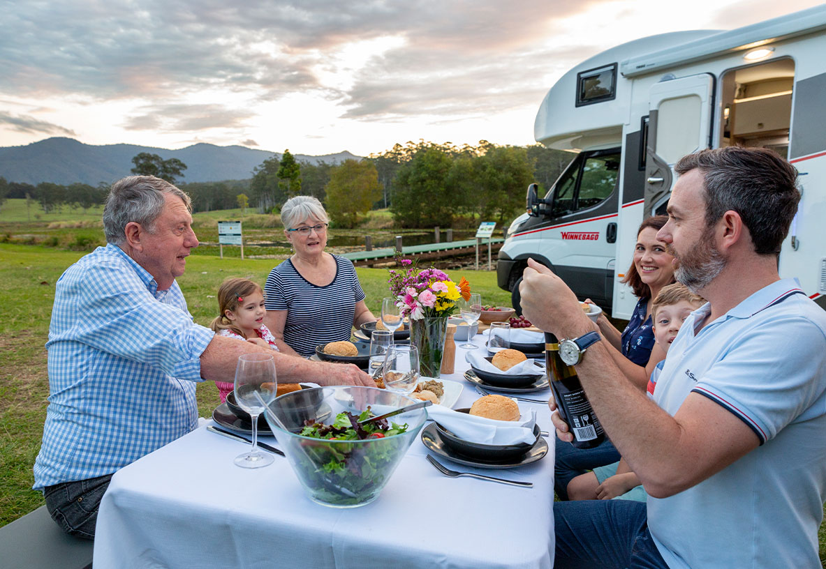 Family enjoying an outdoor meal with Winnebago Motorhome in Background